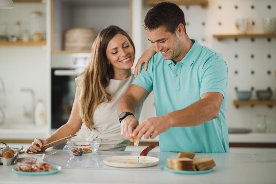 Couple qui cuisine en riant dans une cuisine lumineuse